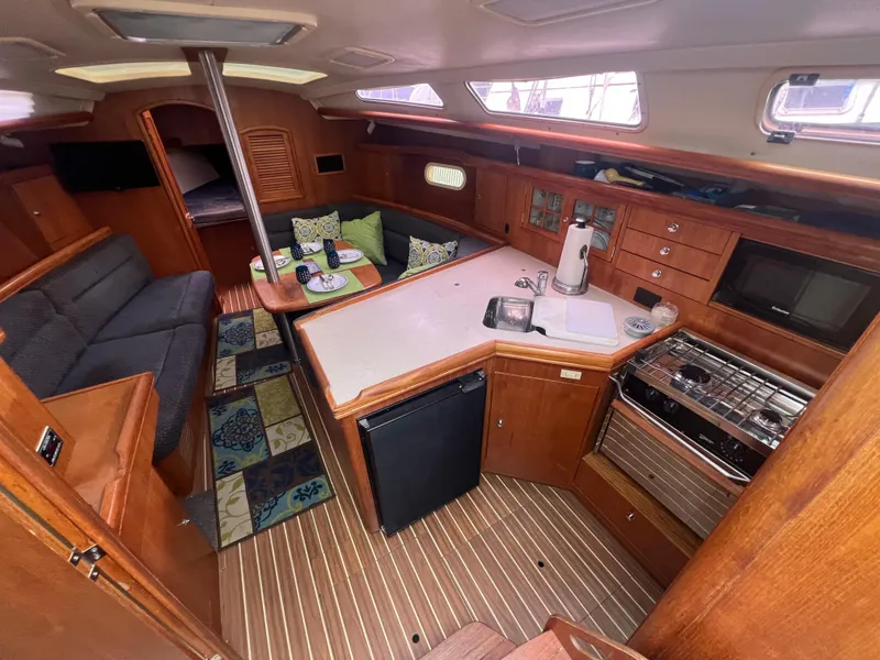 Slide: The Image of 2005 Hunter 36 sailboat interior with kitchen, seating area, and wooden cabinetry. - 27