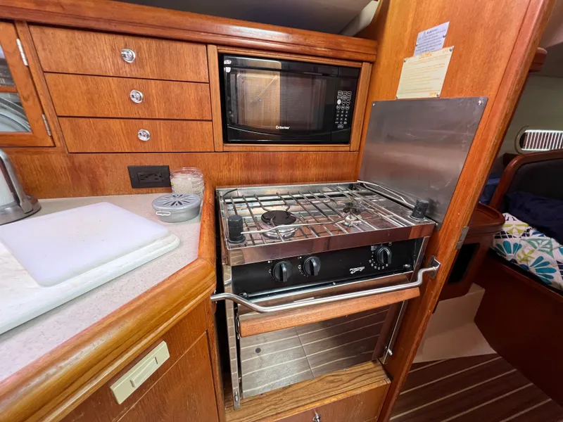Slide: The Image of Hunter 36 2005 yacht kitchen with stove, microwave, and wooden cabinetry. - 30