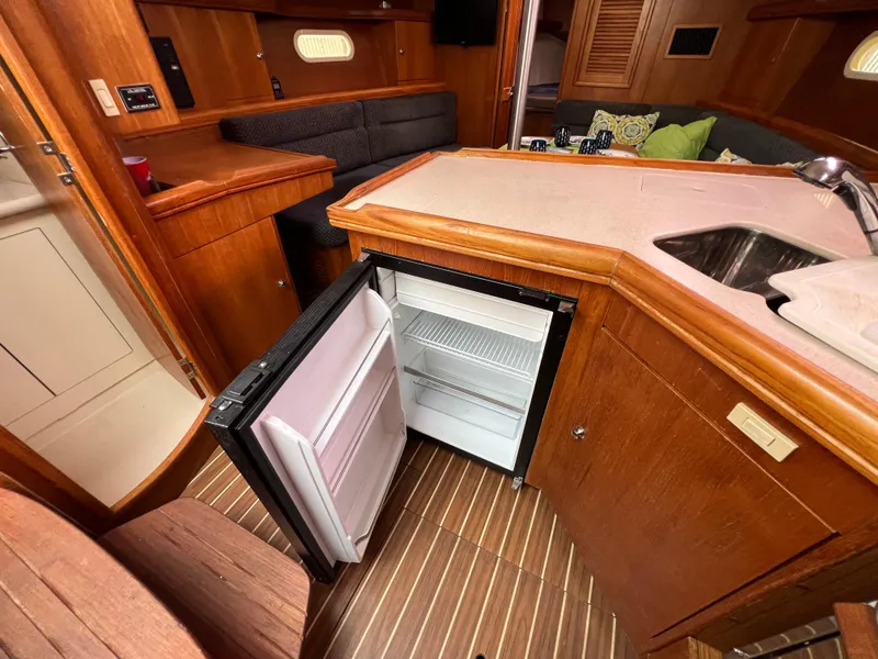 Slide: The Image of Interior of 2005 Hunter 36 sailboat with open fridge, wooden cabinetry, and seating area. - 31