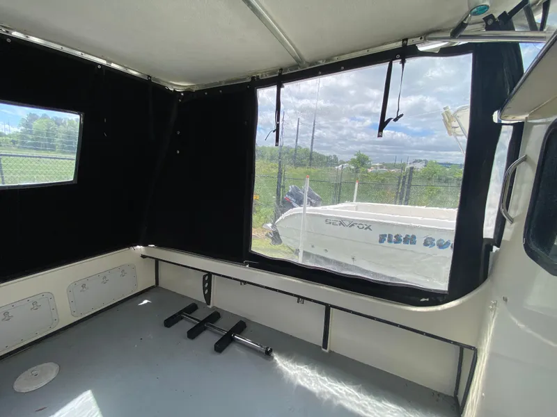 Slide: The Image of Interior view of 2005 C-Hawk Pilothouse 25 boat with black curtains and outdoor scenery. - 16