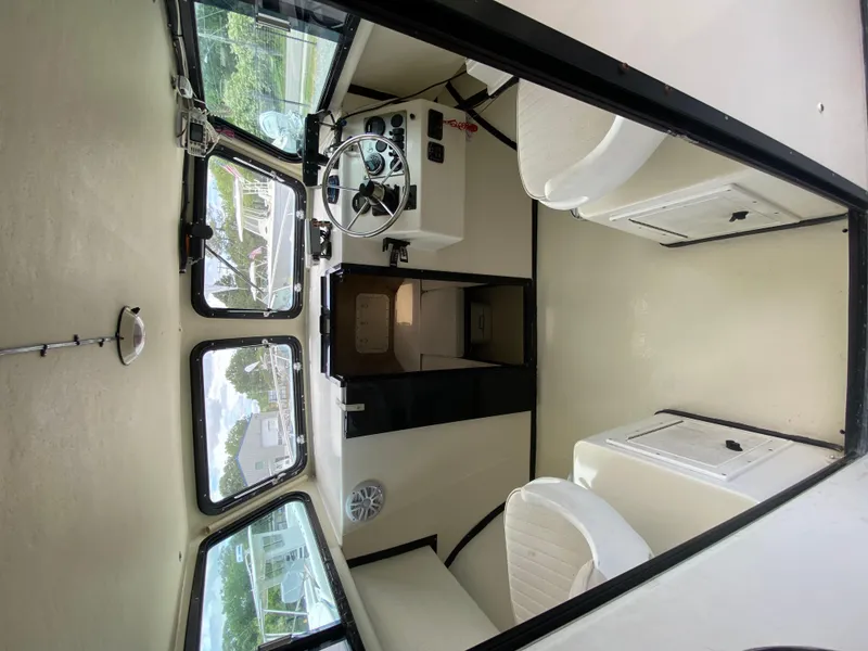 Slide: The Image of Interior of 2005 C-Hawk Pilothouse 25 boat, featuring steering wheel and seating. - 18