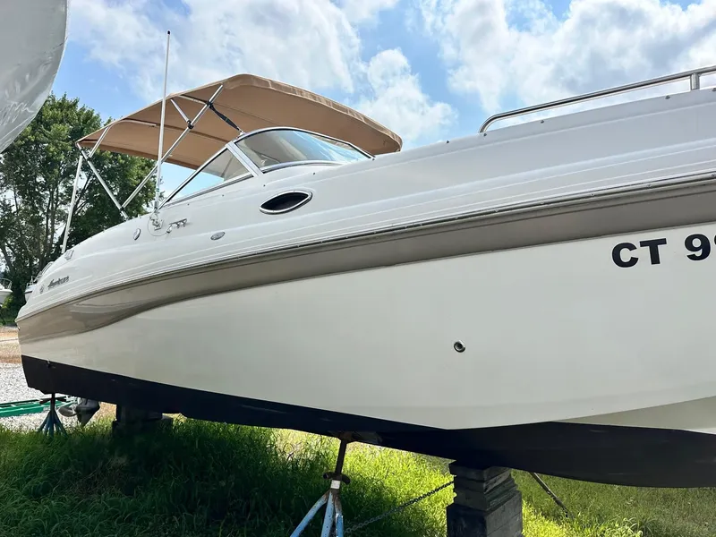 Slide: The Image of 2003 Hurricane 26 SD boat on land with canopy, clear sky background. - 0