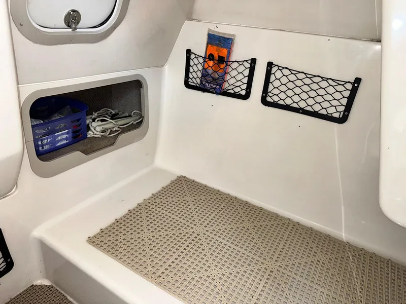 Slide: The Image of 2003 Hurricane 26 SD boat interior with storage compartments and netting. - 13