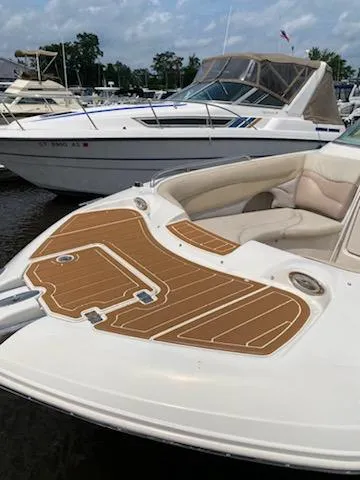 Slide: The Image of 2003 Hurricane 26 SD boat docked with cushioned seating and teak-style deck. - 19