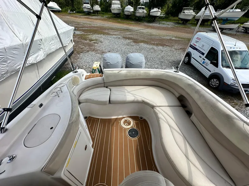 Slide: The Image of 2003 Hurricane 26 SD boat interior with seating and wood flooring in a storage yard. - 20