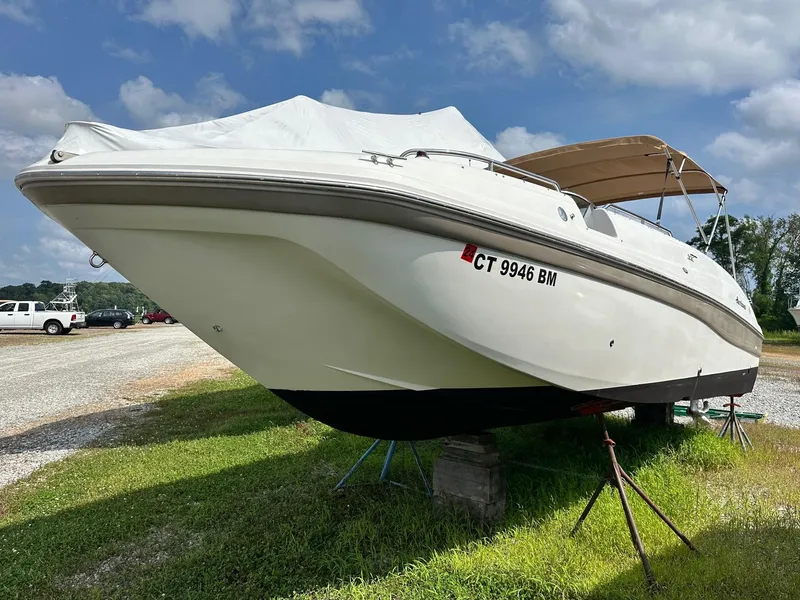 Slide: The Image of 2003 Hurricane 26 SD boat on stands, covered, with blue sky background. - 3