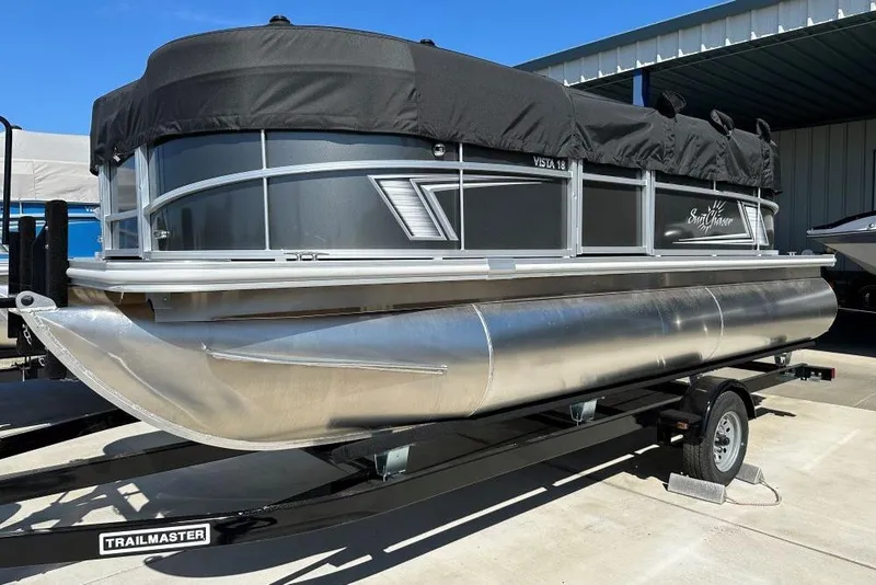 The Image of 2024 SunChaser Vista 18 LR pontoon boat on a trailer, covered and parked outdoors. - 0