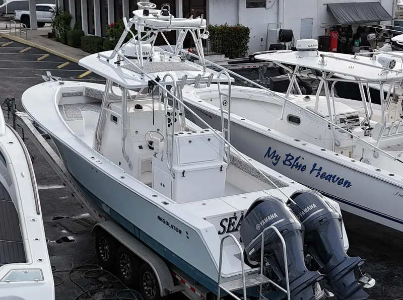 Slide: The Image of 2005 Regulator 32 Forward Seating boat with twin Yamaha engines docked at a marina. - 26