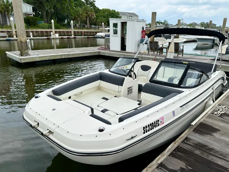 Slide: The Image of 2022 Bayliner DX 2050 boat docked at a marina, featuring sleek design and spacious seating. - 0