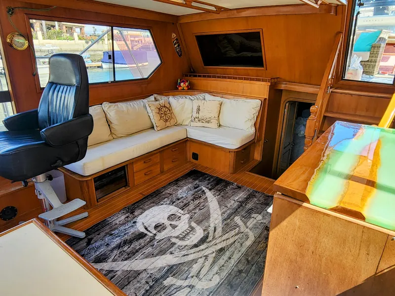 Slide: The Image of 1987 Hi-Star Yacht Fisher 55 interior with seating, captain's chair, and pirate-themed rug. - 27