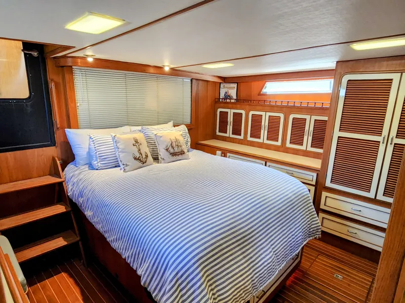 Slide: The Image of 1987 Hi-Star Yacht Fisher 55 master bedroom with striped bedding and wooden cabinetry. - 38