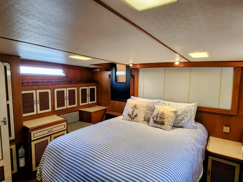 Slide: The Image of 1987 Hi-Star Yacht Fisher 55 bedroom with striped bedding and wooden cabinetry. - 39