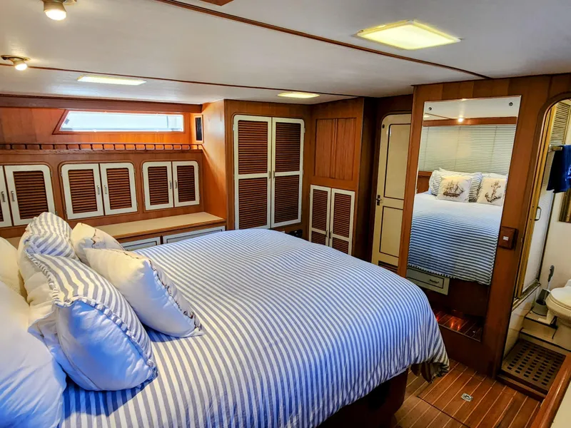 Slide: The Image of Luxurious bedroom interior of 1987 Hi-Star Yacht Fisher 55 with striped bedding and wooden cabinetry. - 40