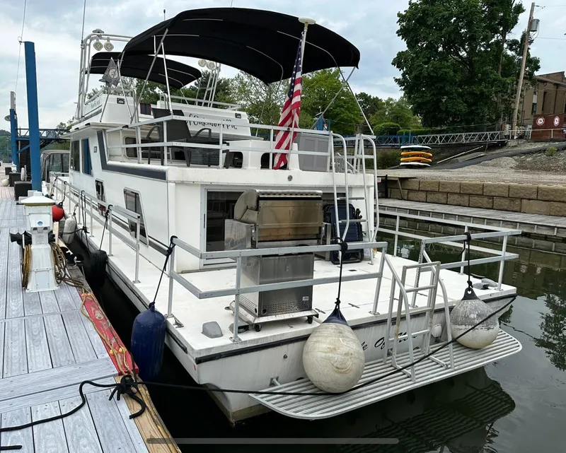 Slide: The Image of A 1990 Gibson 50 Classic yacht docked at a marina with an American flag. - 3