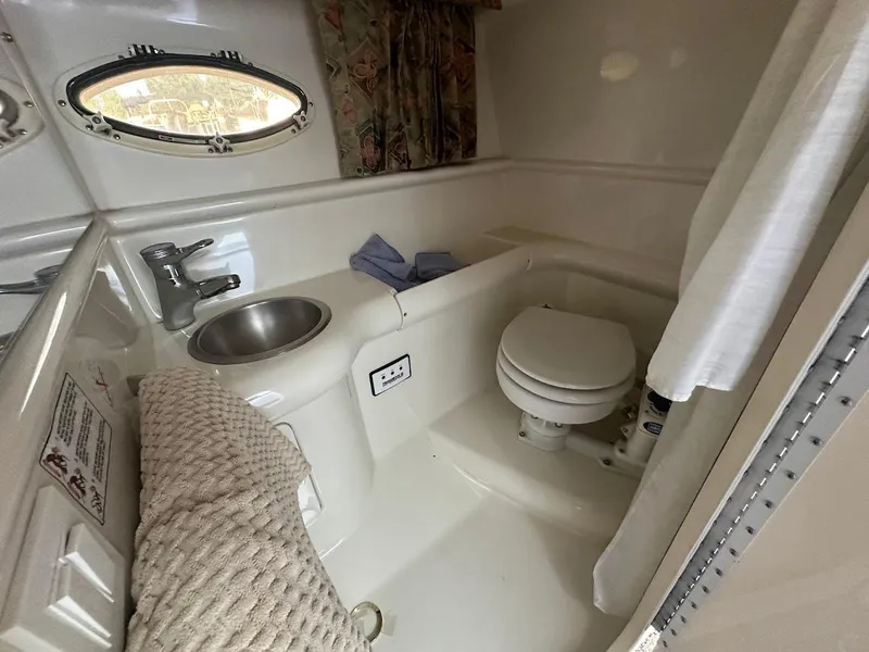 Slide: The Image of 1999 Formula 330 SS boat bathroom with sink, toilet, and porthole window. - 42