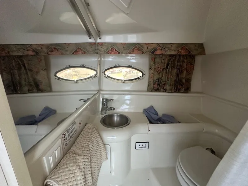 Slide: The Image of 1999 Formula 330 SS boat bathroom with sink, toilet, and porthole windows. - 43