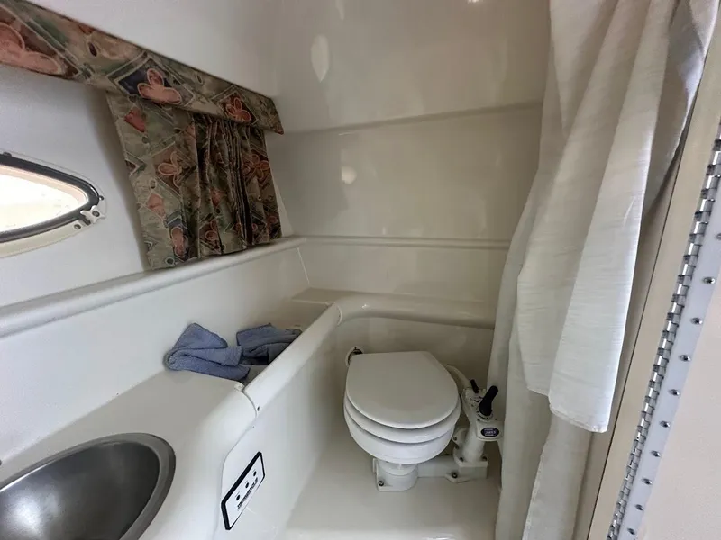 Slide: The Image of 1999 Formula 330 SS boat bathroom with sink, toilet, and shower curtain. - 44