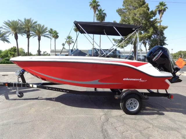 Slide: The Image of 2023 Bayliner Element M17 boat in red on a trailer, parked outdoors. - 16
