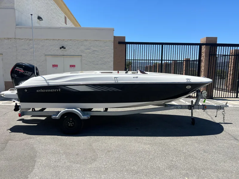 Slide: The Image of 2023 Bayliner Element E18 boat on a trailer in a parking lot. - 2