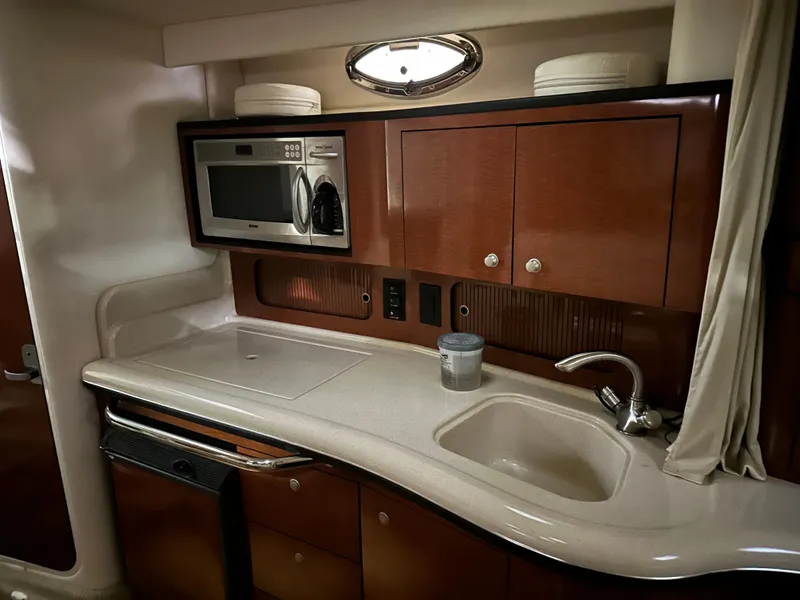 Slide: The Image of 2005 Sea Ray 320 Sundancer galley with microwave, sink, and storage cabinets. - 4