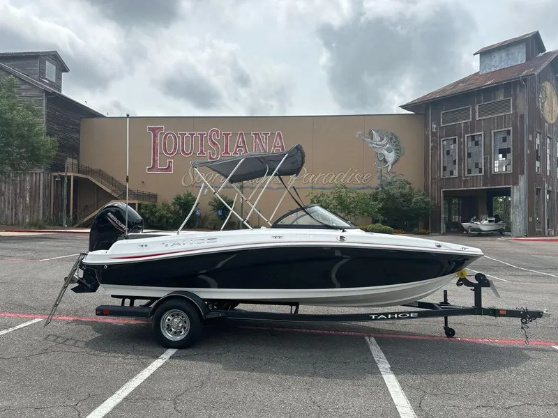 Slide: The Image of 2024 Tahoe 200 S boat on trailer in front of Louisiana-themed building. - 2