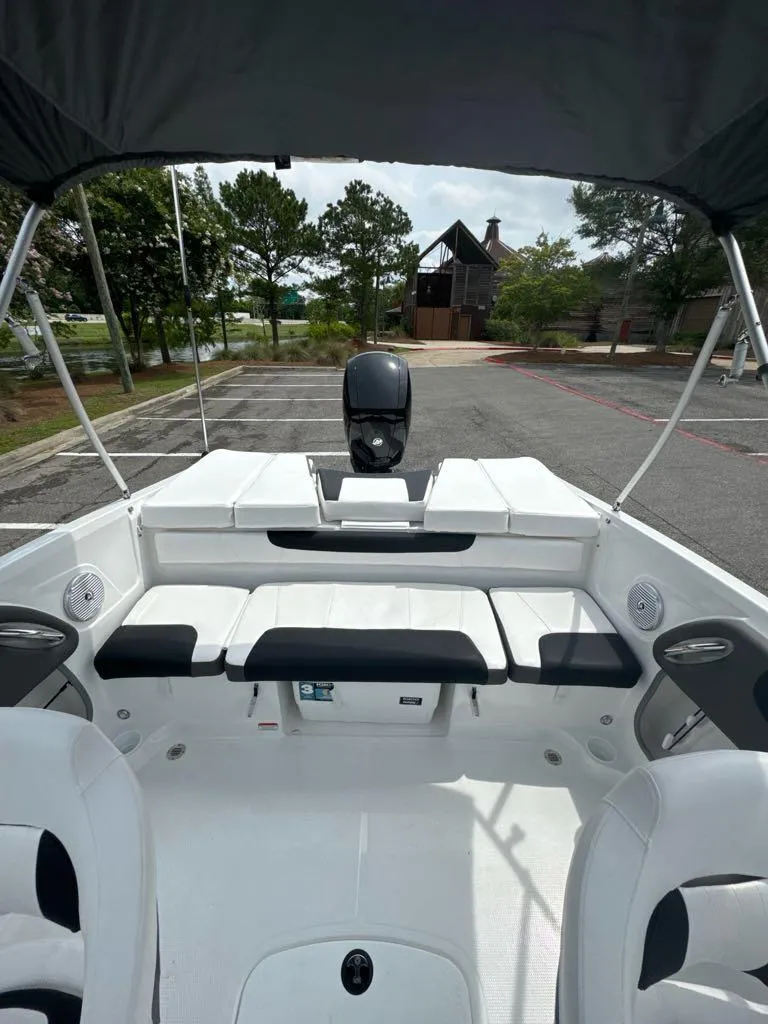 Slide: The Image of 2024 Tahoe 200 S boat interior with seating and motor, parked on a sunny day. - 8