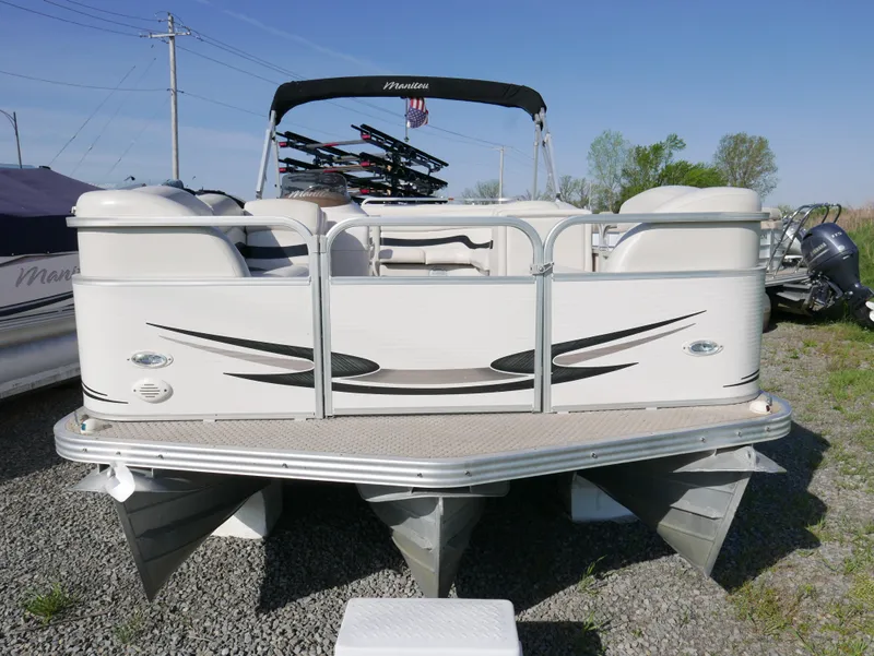 Slide: The Image of 2008 Manitou Oasis pontoon boat with white exterior, docked on gravel. - 2