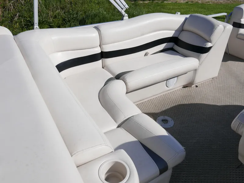 Slide: The Image of 2008 Manitou Oasis boat interior with white and black cushioned seating. - 9