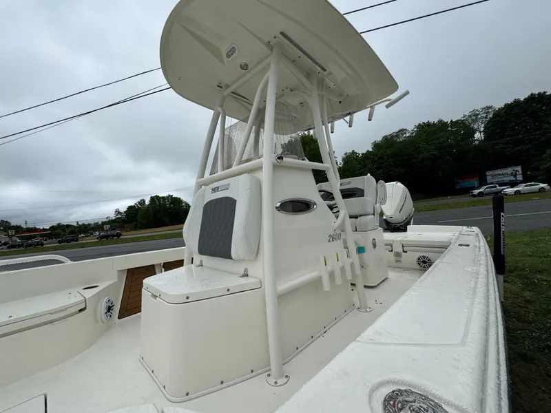 Slide: The Image of 2024 Pathfinder 2600 TRS boat with T-top and seating, parked outdoors. - 6