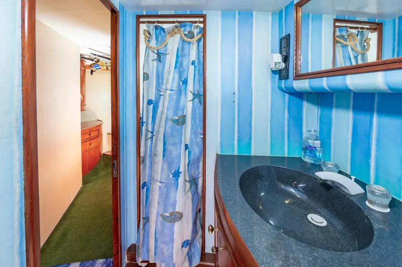 Slide: The Image of Bathroom interior of 1993 Jarrett Bay Convertible yacht with blue striped walls and black countertop. - 46