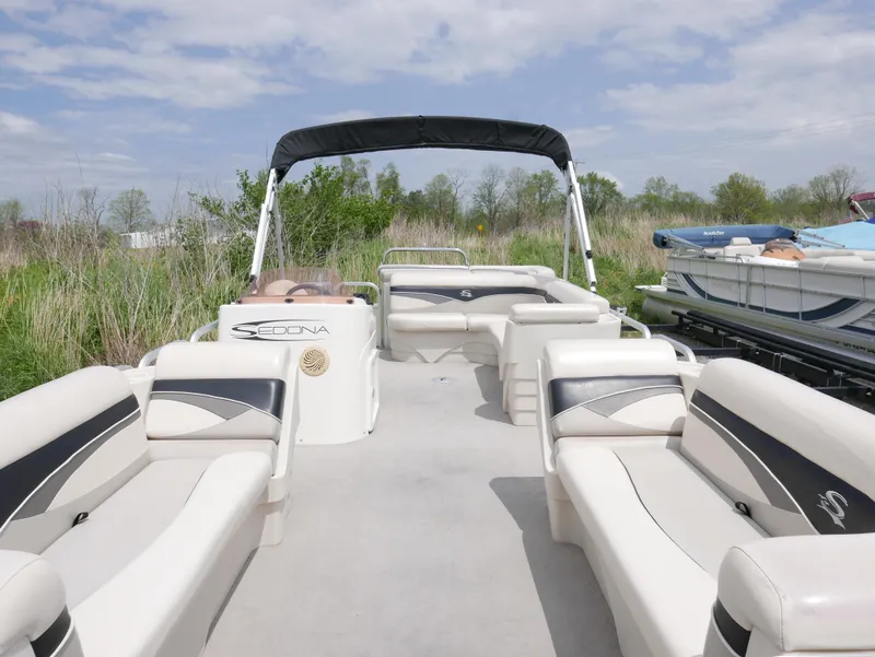 Slide: The Image of 2007 Sedona L23 pontoon boat with spacious seating and canopy, docked near grassy shoreline. - 3