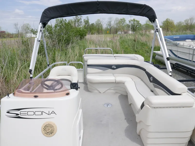 Slide: The Image of 2007 Sedona L23 pontoon boat with seating, canopy, and steering console, docked near grassy shoreline. - 5
