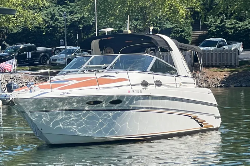 Slide: The Image of 1999 Sea Ray 290 Sundancer boat on calm water near a dock. - 2