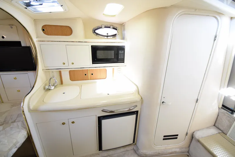 Slide: The Image of 1999 Sea Ray 290 Sundancer galley with microwave, sink, and mini-fridge. - 24
