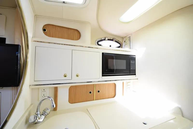 Slide: The Image of 1999 Sea Ray 290 Sundancer galley with microwave, sink, and storage cabinets. - 26