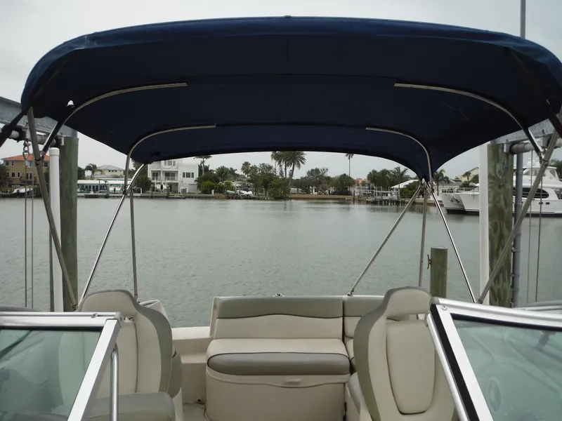 Slide: The Image of 2007 Sea Ray 240 Sundeck boat with blue canopy on a calm waterfront. - 28