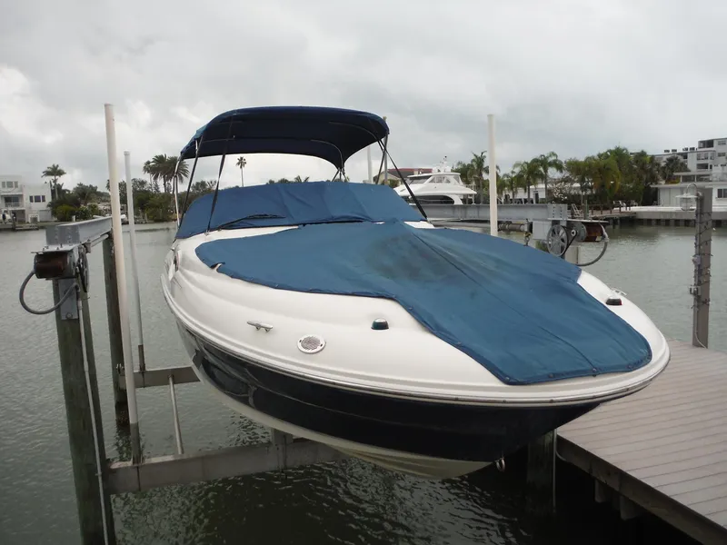 Slide: The Image of 2007 Sea Ray 240 Sundeck boat with blue cover on lift in marina. - 35