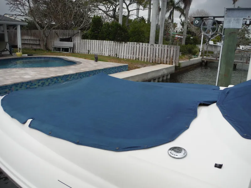 Slide: The Image of 2007 Sea Ray 240 Sundeck with blue cover docked near a pool. - 32