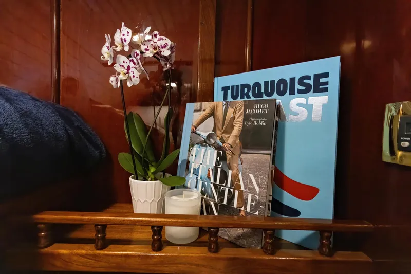 Slide: The Image of Books and orchid on a shelf inside a 1929 Lyman-Morse Staysail Schooner. - 47