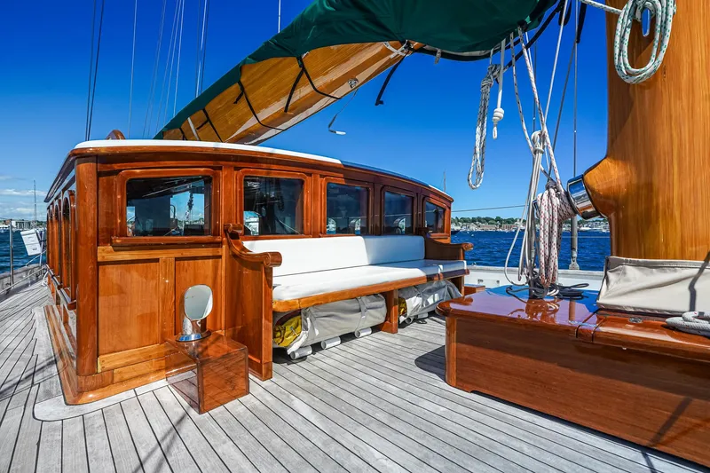 Slide: The Image of 1929 Lyman-Morse Staysail Schooner deck with polished wood and seating, under clear blue sky. - 9