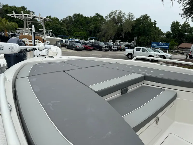 Slide: The Image of 2024 Ranger 2510 boat with gray seating, docked near a parking lot and trees. - 9