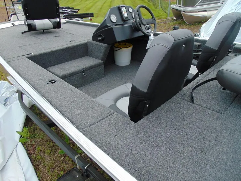 Slide: The Image of 2024 Crestliner 1600 Storm boat interior with gray carpet and black seats. - 5