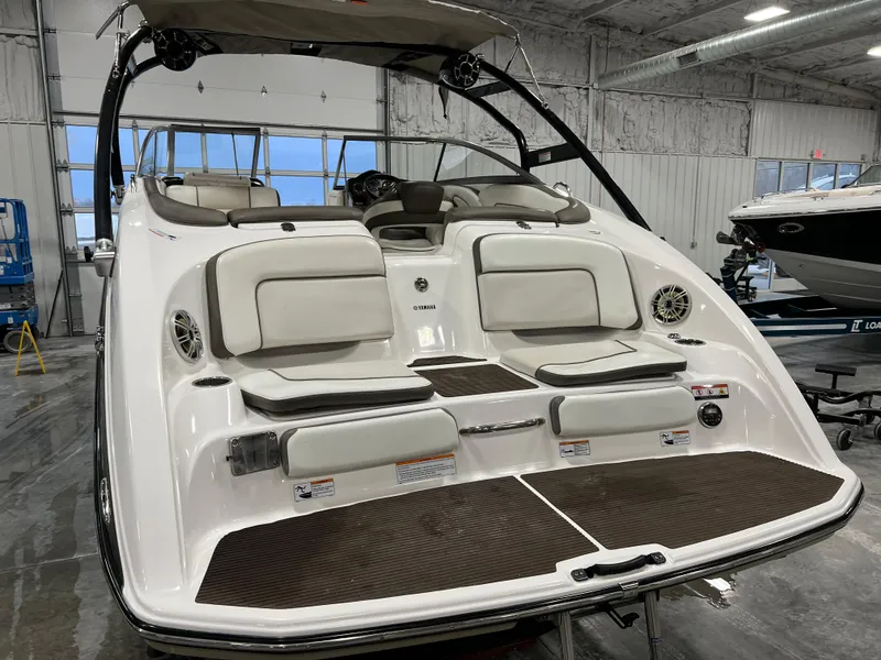 Slide: The Image of 2013 Yamaha Boats 242 Limited S, white, in a showroom, rear view with seating and swim platform. - 5