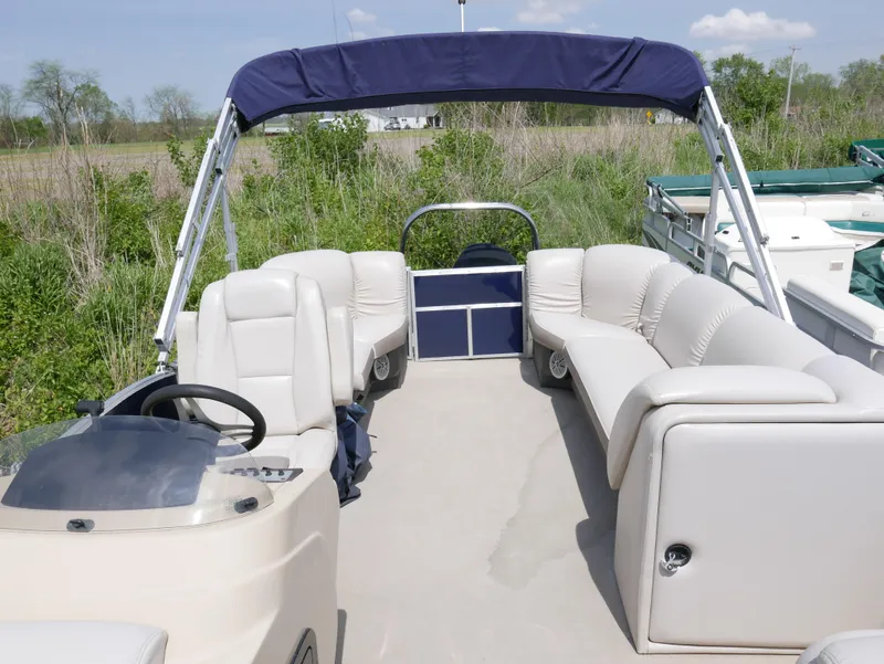 Slide: The Image of 2017 Sweetwater SWPE 255 SB pontoon boat with beige seating and blue canopy. - 4