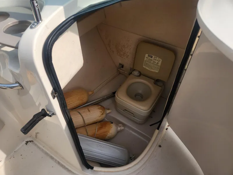 Slide: The Image of 2003 Sea Ray 220 Sundeck boat storage compartment with portable toilet and fenders. - 12