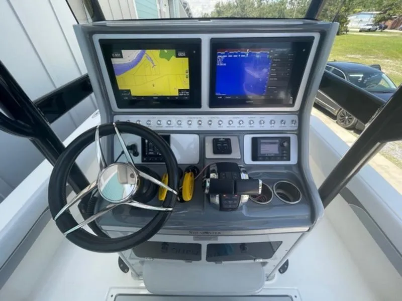 Slide: The Image of 2020 ShearWater 270 Carolina Flare boat dashboard with dual navigation screens and steering wheel. - 17