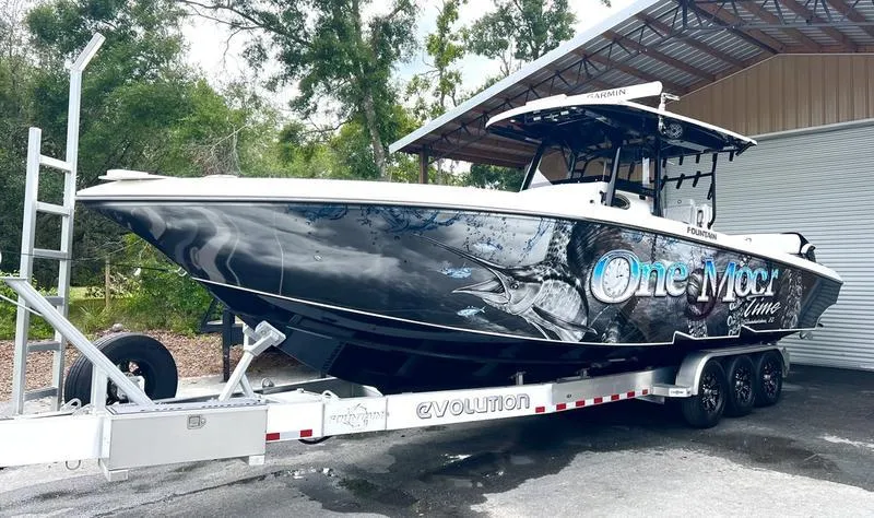 Slide: The Image of 2022 Fountain 34 TE boat on a trailer, parked outdoors near a building. - 10