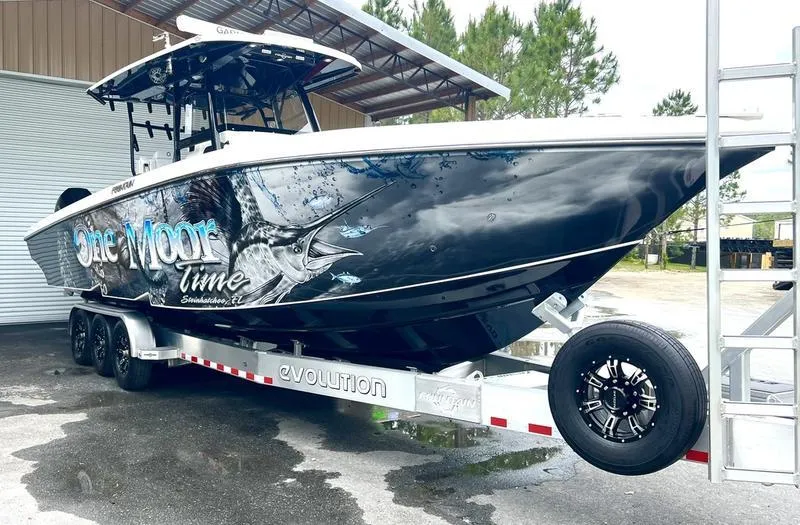Slide: The Image of 2022 Fountain 34 TE boat on trailer with custom graphics, parked outdoors. - 8