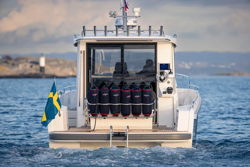Slide: The Image of 2024 Nimbus C11 boat on water, Swedish flag, rear view, scenic background. - 3