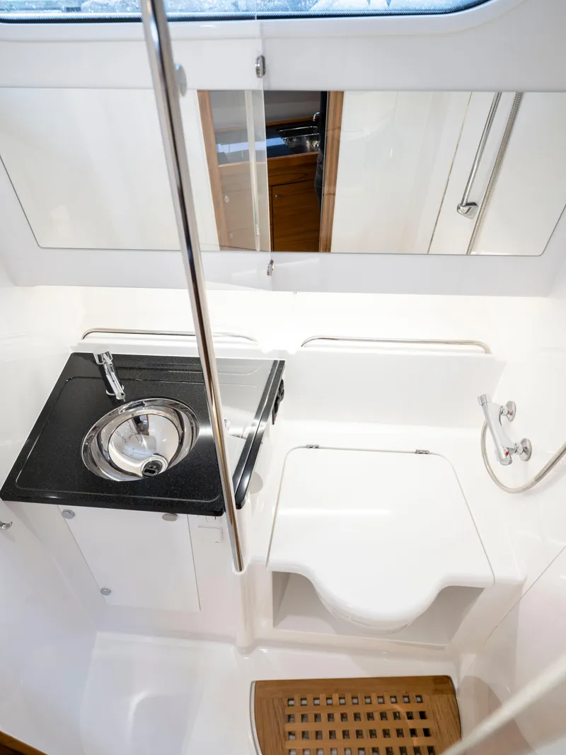 Slide: The Image of 2024 Nimbus C11 boat bathroom with sink, toilet, and wooden floor mat. - 15